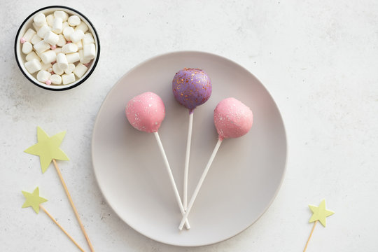 Three sweet cake pops on a plate on a white background. dessert for kids party. horizontal image. top view. copy space.