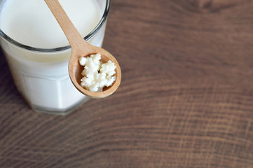 Kefir grains in wooden spoon and kefir drink in glass