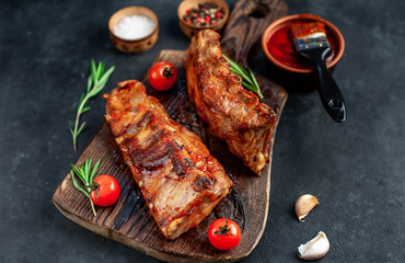 Grilled pork ribs with spices on a cutting board on a stone background