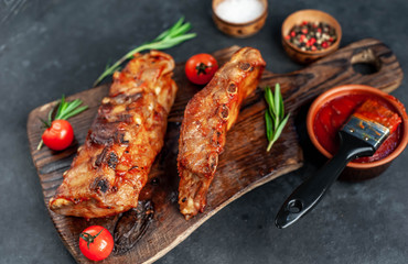 Grilled pork ribs with spices on a cutting board on a stone background