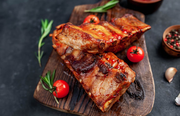 Grilled pork ribs with spices on a cutting board on a stone background