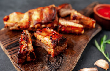 Grilled pork ribs with spices on a cutting board on a stone background