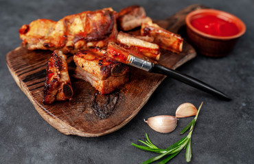 Grilled pork ribs with spices on a cutting board on a stone background
