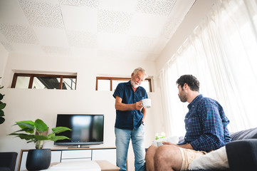 Obraz premium The elderly father and middle-aged son Talking in the house With a coffee cup in hand, Concepts of family and stay at home