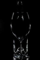 Silhouette of a glass with bottle of wine behind with black background