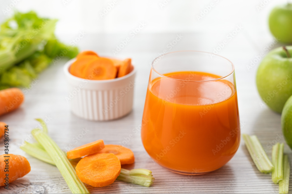 Sticker glass with carrot juice, celery and green apple on the table.