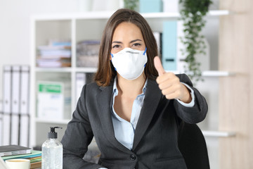 Executive wearing mask with thumbs up looking camera