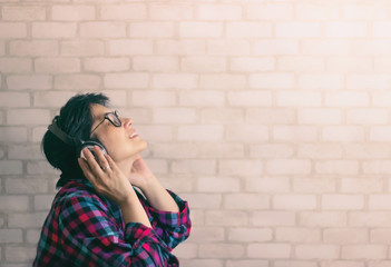 A young brunette woman with her head raised from pleasure to the top listens to music through...