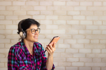 A young brunette woman listens to music through headphones from a smartphone. Talking on the phone...
