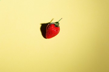 red strawberry on a sheet of yellow canton