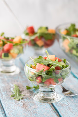 A close up view of a serving of watermelon arugula salad with more salads in behind.