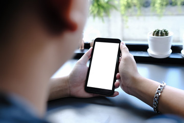 Mockup image of a woman holding and showing black mobile phone with blank screen in cafe.