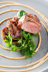 Delicious grilled beef medallions with sauce and salad served on grey plate