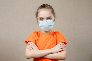 Portrait of a Little girl in a medical mask. Kid patient stands against the wall background, copy space for text