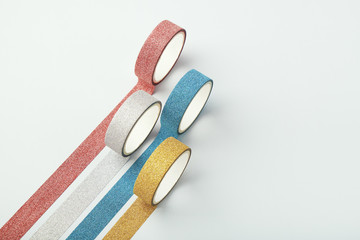 Four rolls of glitter tape and parallel strips on white background