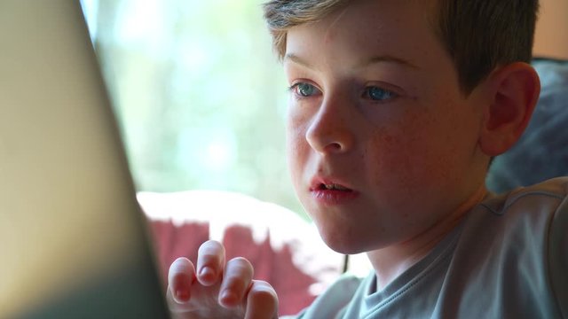 Close up of child&rsquo;s face doing schoolwork at home on laptop