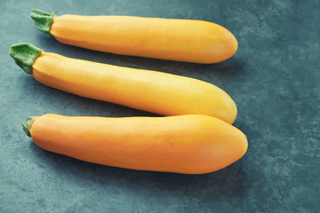 Three yellow zucchini on kitchen table. Whole raw courgettes