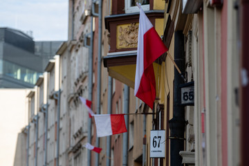 Fototapeta na wymiar Polish state flags hung on the walls of the houses of the city