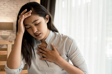 Portrait of 20s young Asian woman having difficulty breathing in bedroom at night. Shortness of...