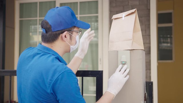 Contactless delivery concept. Delivery asian man or post man pull down food paper bag at front of home with social distance, quarantine to protect form coronavirus. New normal delivery service.