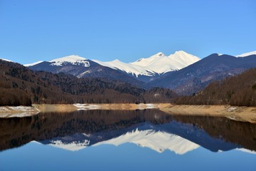 Fototapeta na wymiar snowy mountains reflecting in the lake with blue sky