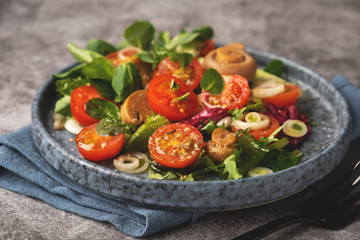 vegetarian salad of leaves, tomatoes, pickled champignon mushrooms, close-up, healthy food