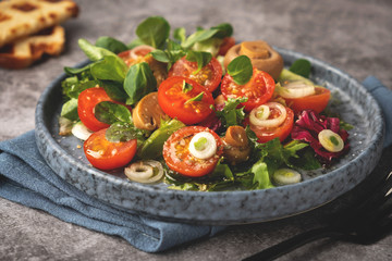 vegetarian salad of leaves, tomatoes, pickled champignon mushrooms, close-up, healthy food