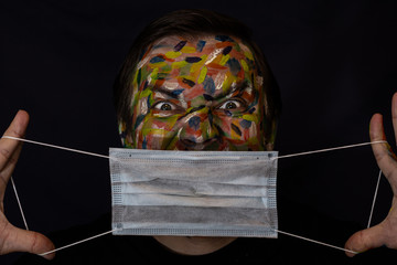 Face of a man close-up on a black background. The painted face of a confident man in a medical bandage. Concept photo for fighting viruses.