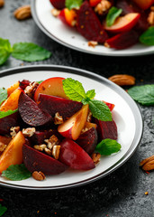 Vegan Plum, beet salad with pecan nuts, mint and herbs on rustic black table