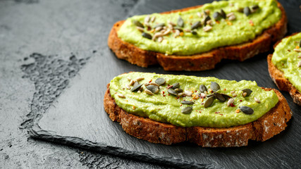 Healthy Homemade Avocado creamy Toast with nuts mix on rustic stone board