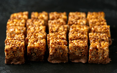 Crispy rice bar, snack with caramel and chocolate on rustic background