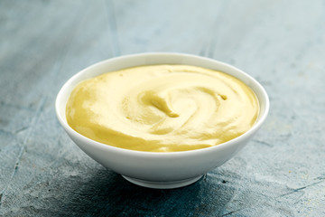 Dijon mustard in white bowl on rustic background