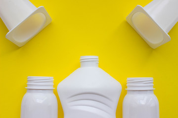 White plastic bottles on yellow background with place for your design. Top view