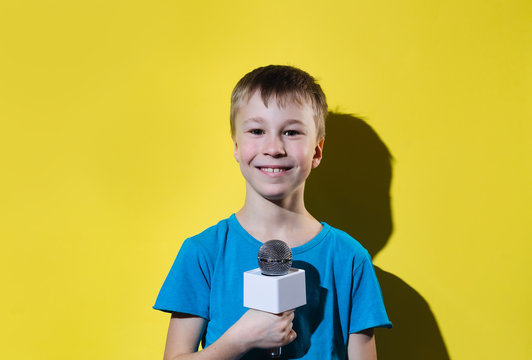 Little happy journalist with microphone isolated on yellow color background.