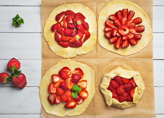 Process Preparation of galette from shortcrust pastry and fresh strawberries. Flat lay, four biscuits on baking paper. Homemade pastry