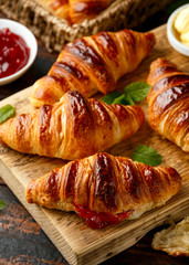 Freshly baked croissants with butter, strawberry jam and tea for breakfast or brunch