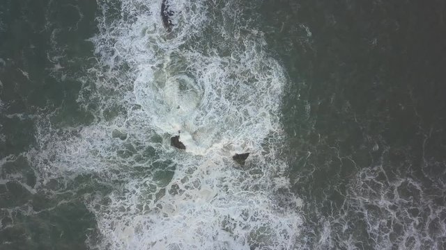 Waves crash against the rocks. An iconic place on the Atlantic coast, the Mecca of surfing on big waves.Rocks at the Nazare Lighthouse, the place with the largest waves in Europe, Nazare, Portugal.