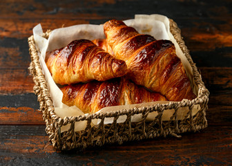 Freshly baked croissants with butter in wooden tray