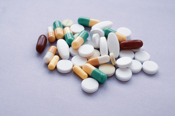 Colorful pills and capsules on a purple background, macroshot tablets 