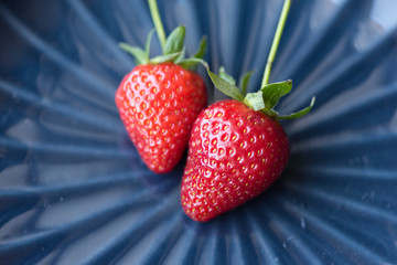 Two strawberries on a relief blue background, macro