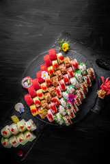 set of sushi roll with salmon, avocado, cream cheese, cucumber, tuna, rice, caviar, eel on black wooden table background
