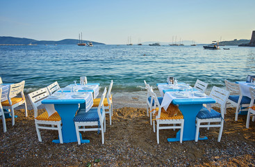 Cute chairs and table on the beach at seaside restaurant in Bodrum