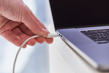 Laptop charger in hands close up. Discharged low battery at computer