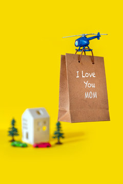 Yellow paper bag gift toy house tree delivery helicopter fly copy space background I love you mum