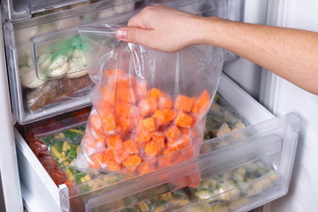 Bags with frozen vegetables in refrigerator. Frozen pumpkin cubes