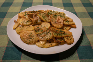 home made crispy seasoned cottage fries with parsley on a white plate