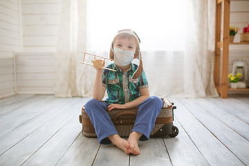 Little cute kid boy in quarantine at home dreams of traveling.