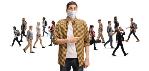Disappointed man with a protective face mask pointing at a group of people walking without masks