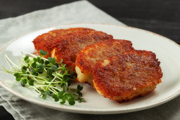 Potato pancakes with sour cream and dill on a wooden table