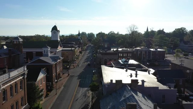 Aerial camera flying into the sun, low over houses along the mainstream in Charles Town, WV.